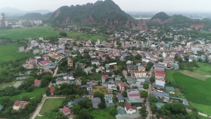 Ảnh flycam khu dân cư hiện hữu ở Xuân Mai với nhà ở san sát, ruộng và dãy núi đá phía sau